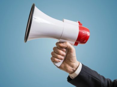 mavi arka plan önünde beyaz bir megafon tutan el