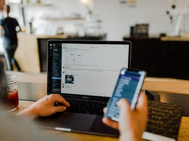 Bir eliyle telefon tutan, diğer eliyle bilgisayarı tutan birisi