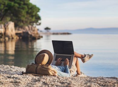 Freelance nedir sorusuna yanıt niteliğinde deniz kıyısında güneşlenirken bilgisayarı ile çalışan kadın